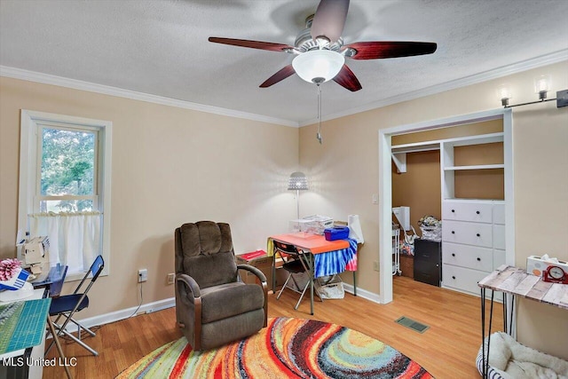 sitting room with ornamental molding, hardwood / wood-style floors, a textured ceiling, and ceiling fan