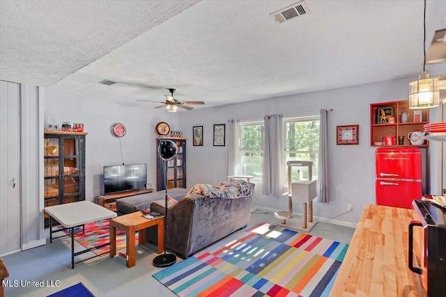 living room featuring ceiling fan, a textured ceiling, and concrete flooring