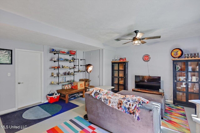 living room with ceiling fan, a textured ceiling, and concrete floors