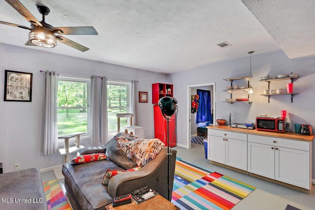 living room with a textured ceiling and ceiling fan