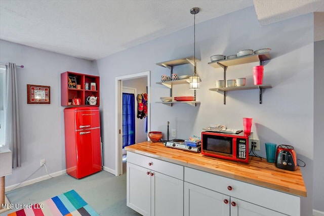 kitchen with butcher block counters, a textured ceiling, pendant lighting, and white cabinets