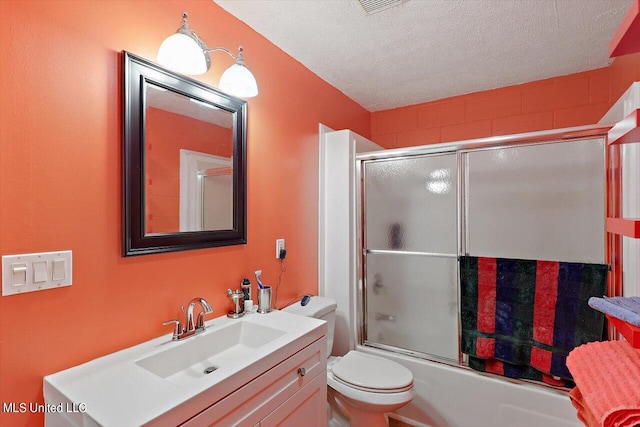 full bathroom with toilet, a textured ceiling, vanity, and shower / bath combination with glass door