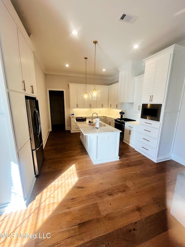 kitchen featuring dark hardwood / wood-style floors, decorative light fixtures, a kitchen island with sink, white cabinets, and appliances with stainless steel finishes