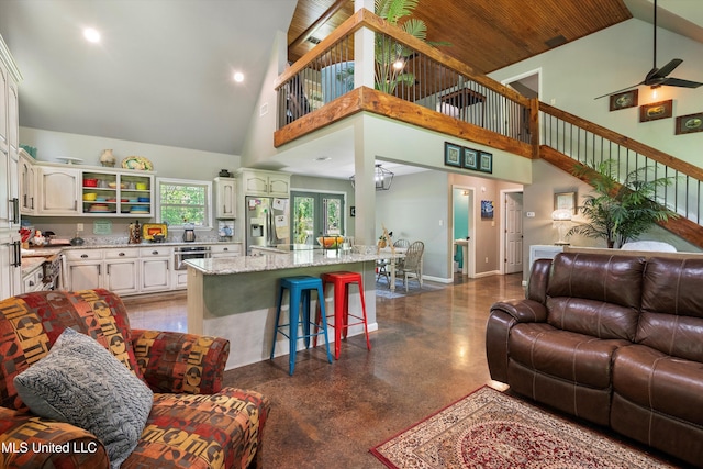 living area with baseboards, high vaulted ceiling, recessed lighting, a ceiling fan, and concrete floors