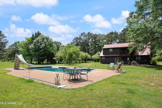 outdoor pool with a lawn, a patio area, and a water slide