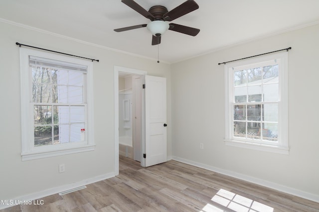 empty room with baseboards, light wood-style floors, visible vents, and a healthy amount of sunlight