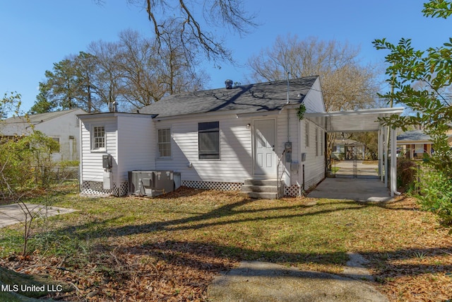 exterior space with a yard, central air condition unit, entry steps, a gate, and an attached carport