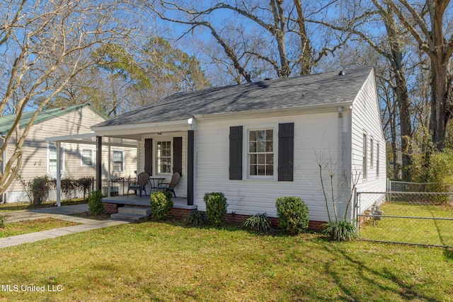 view of front facade with a shingled roof, a front yard, covered porch, and fence