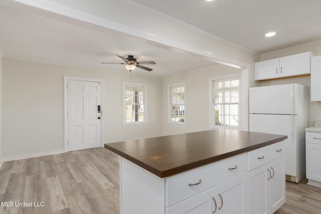 kitchen featuring light wood finished floors, white cabinets, crown molding, and freestanding refrigerator