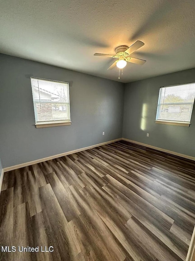 unfurnished room with a textured ceiling, dark wood-type flooring, and baseboards