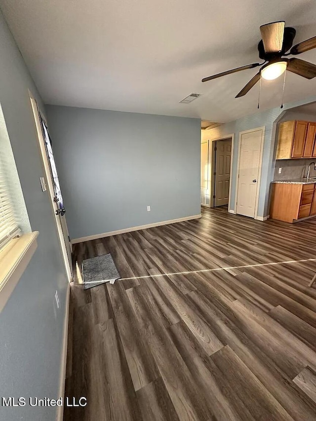 unfurnished living room featuring visible vents, baseboards, ceiling fan, and dark wood-style flooring