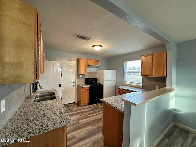 kitchen with light wood finished floors, black range with gas cooktop, visible vents, freestanding refrigerator, and a sink