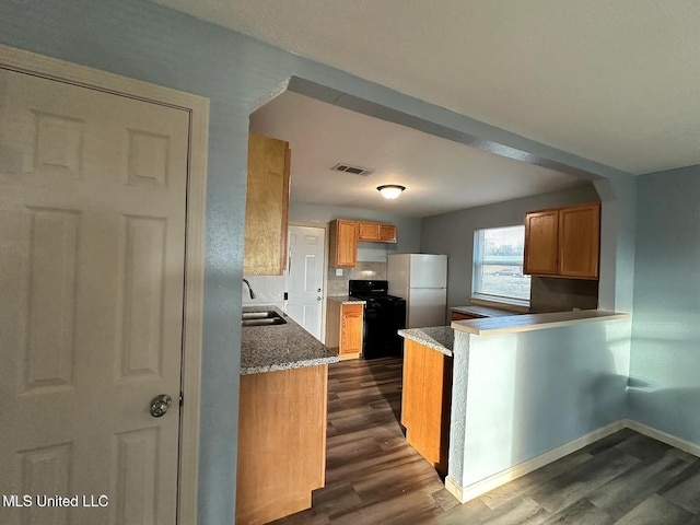 kitchen featuring visible vents, dark wood-type flooring, freestanding refrigerator, gas stove, and a sink