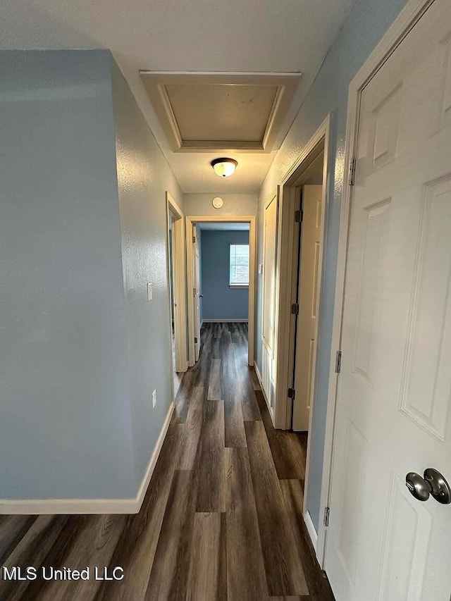 corridor with dark wood-style floors and baseboards