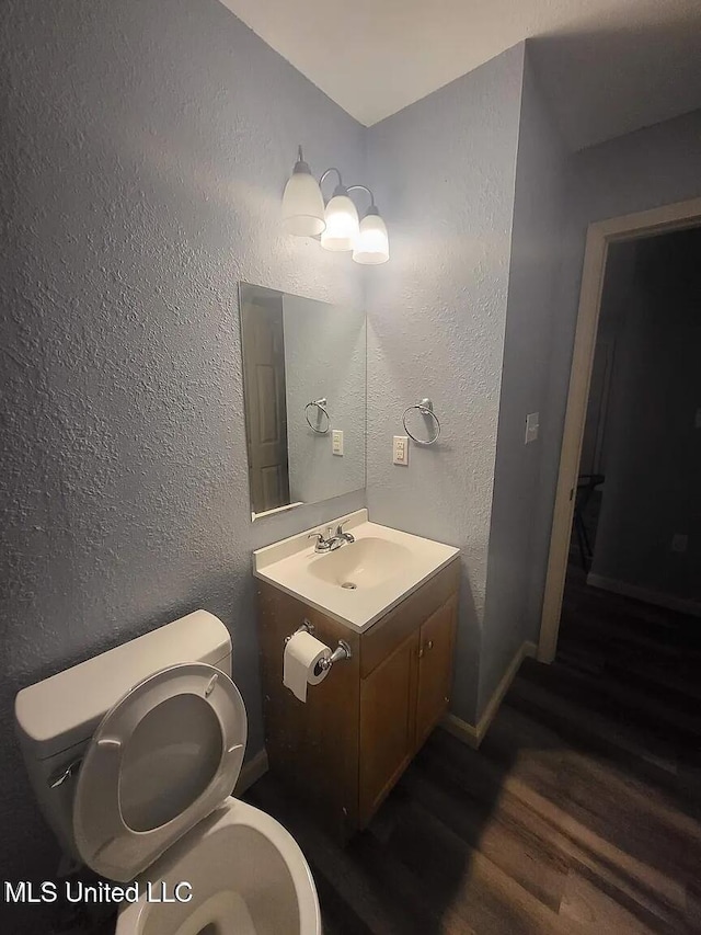 bathroom featuring a textured wall, toilet, and wood finished floors