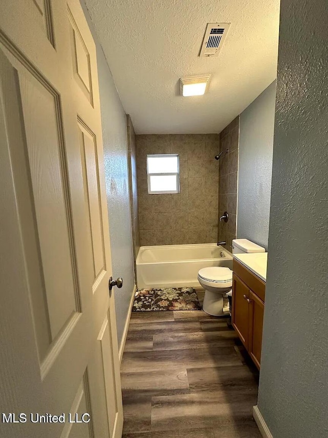 bathroom featuring visible vents, a textured wall, wood finished floors, a textured ceiling, and shower / washtub combination