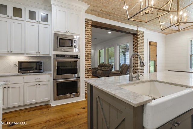 123 Klaas Blvd, Madison, MS 39110 - kitchen featuring appliances with stainless steel finishes, light wood-type flooring, a chandelier, white cabinetry, and light stone countertops