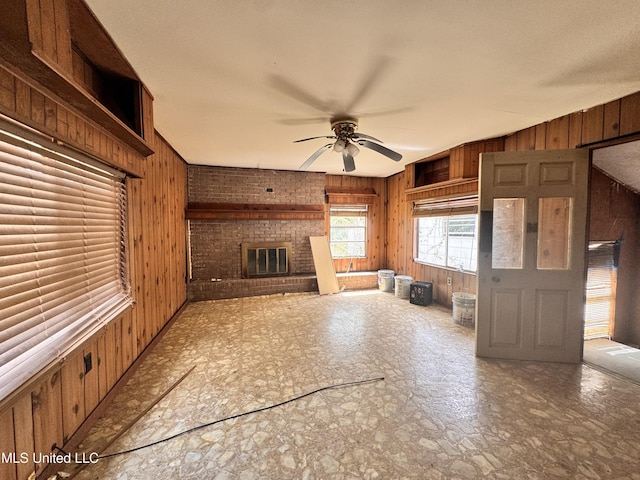 341 Savanna St, Jackson, MS 39212 - unfurnished living room featuring a ceiling fan, a brick fireplace, wood walls, and stone finish flooring
