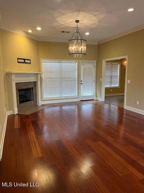 unfurnished living room featuring hardwood / wood-style flooring, crown molding, and an inviting chandelier