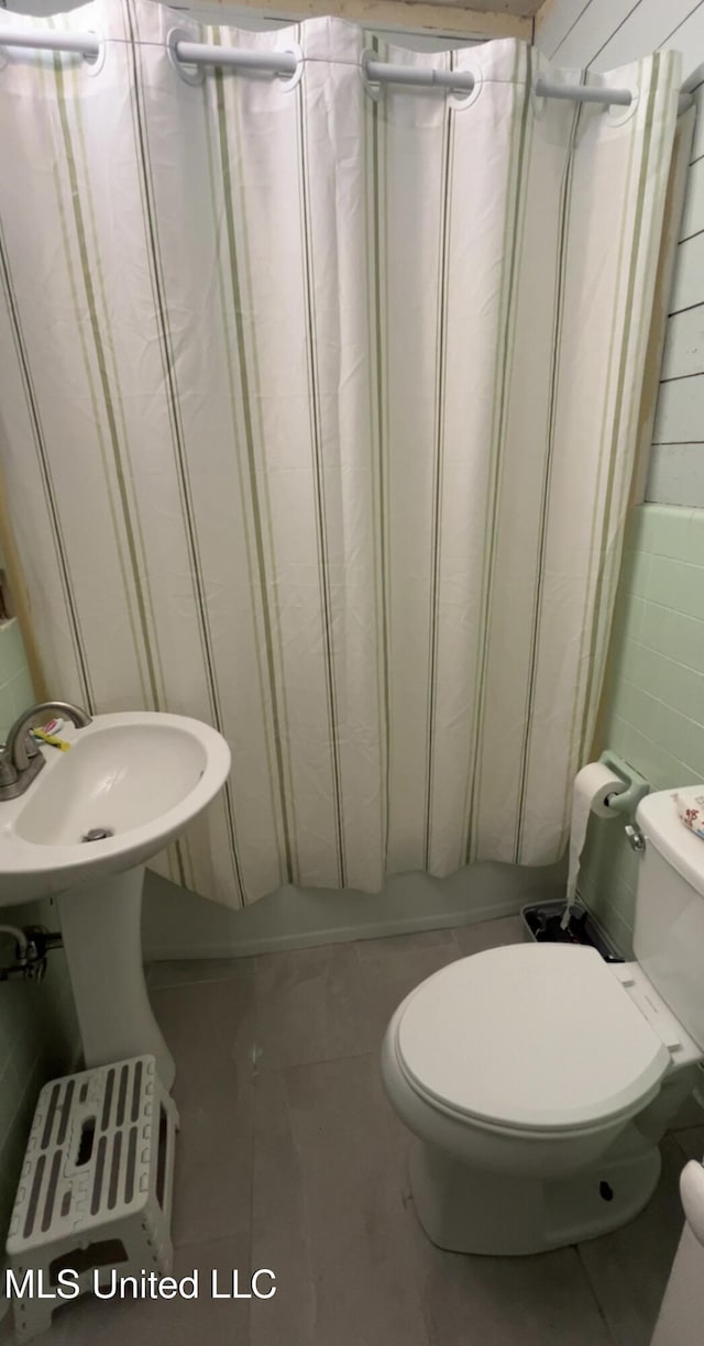 1006 Lamar St, Cleveland, MS 38732 - full bath featuring toilet, a shower with curtain, tile walls, and tile patterned floors