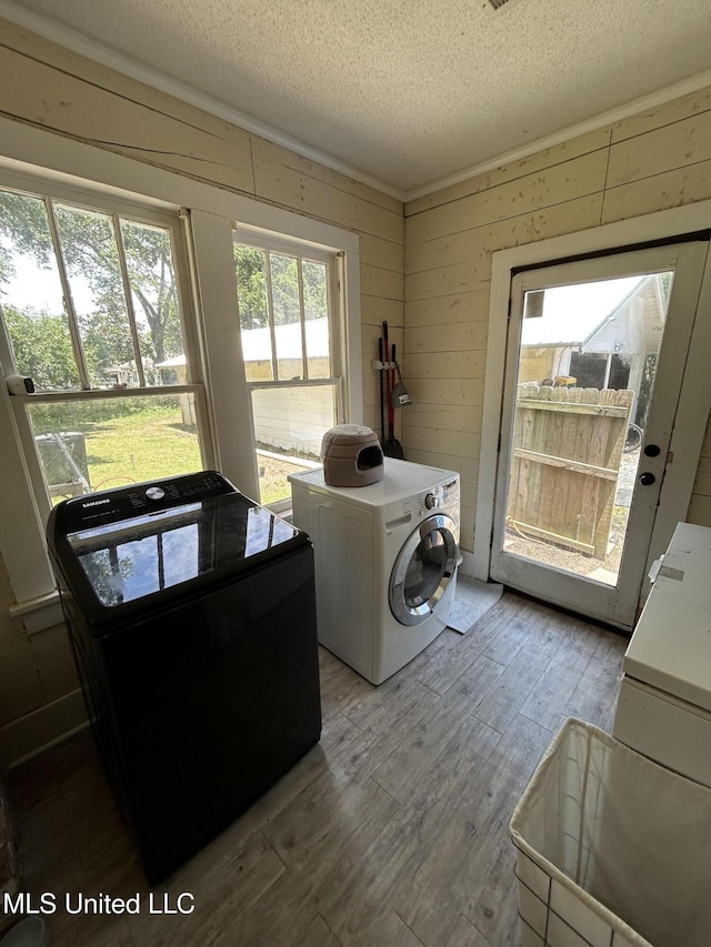 1006 Lamar St, Cleveland, MS 38732 - laundry room with light wood finished floors, a textured ceiling, washing machine and clothes dryer, and wooden walls