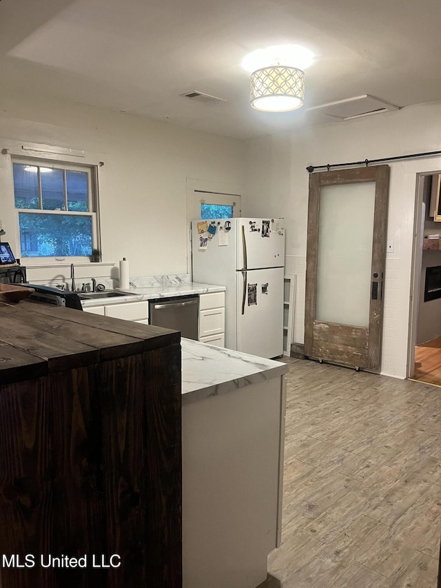 1006 Lamar St, Cleveland, MS 38732 - kitchen featuring freestanding refrigerator, dishwasher, light wood-style flooring, white cabinetry, and a sink