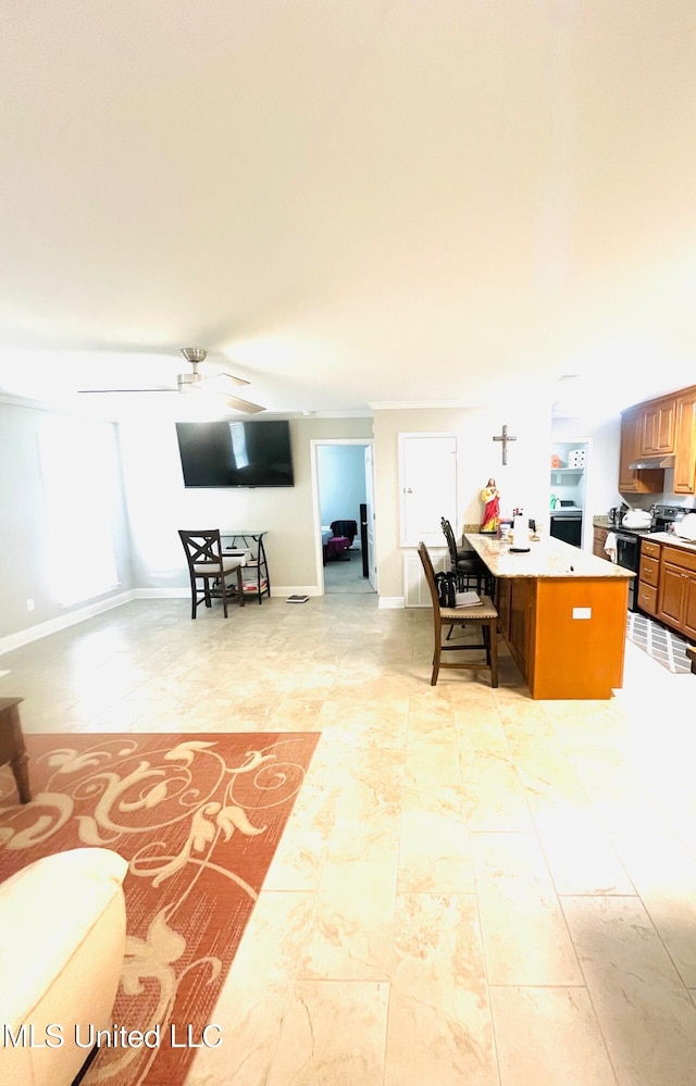 interior space with light countertops, a kitchen breakfast bar, a ceiling fan, open floor plan, and brown cabinetry