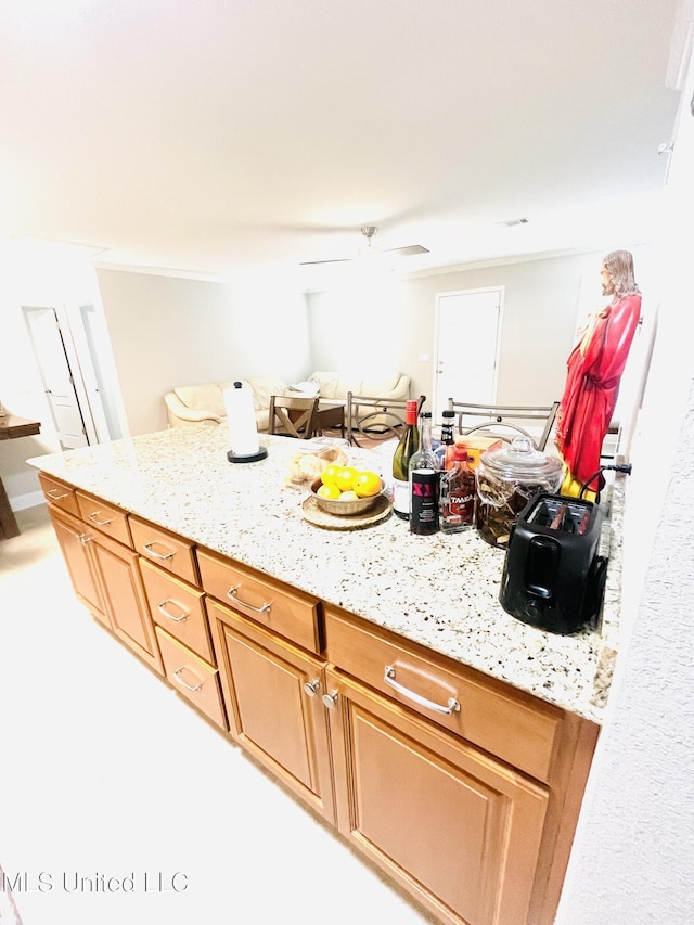 kitchen with a ceiling fan and light stone counters