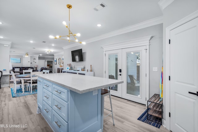 kitchen with a breakfast bar, decorative light fixtures, a center island, ornamental molding, and light hardwood / wood-style floors