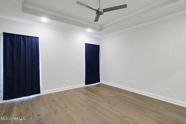 spare room with hardwood / wood-style floors, ornamental molding, a tray ceiling, and ceiling fan