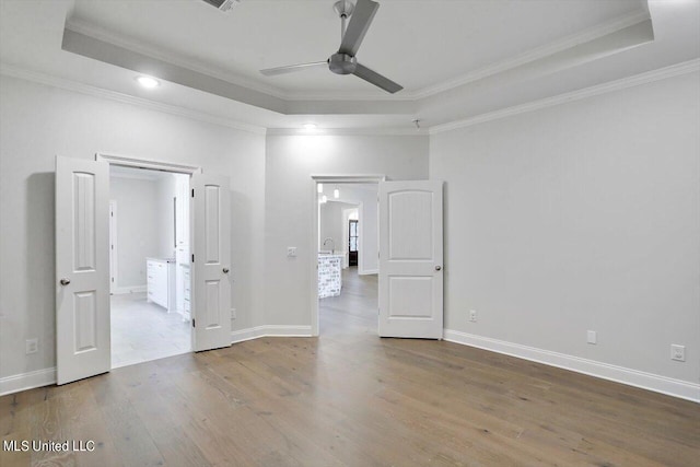 spare room with ceiling fan, crown molding, a tray ceiling, and hardwood / wood-style floors