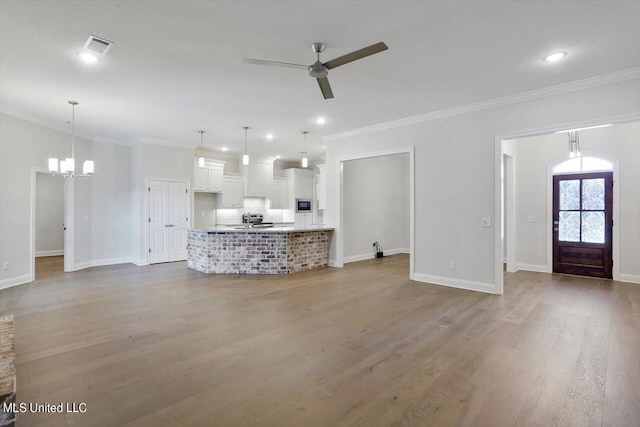 unfurnished living room featuring crown molding, wood-type flooring, and ceiling fan with notable chandelier