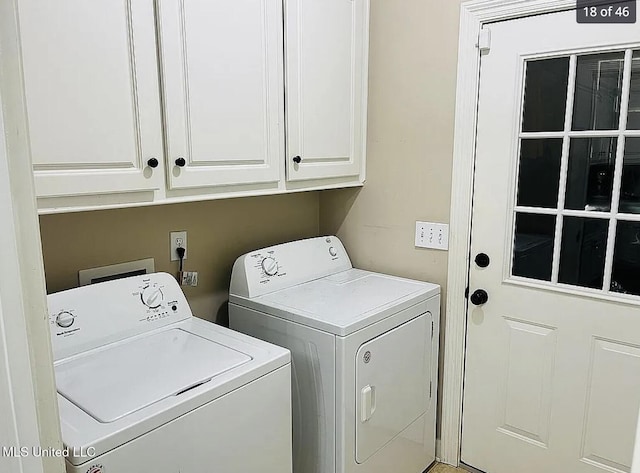 clothes washing area with washing machine and dryer and cabinets