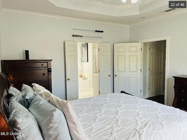 bedroom featuring connected bathroom, a raised ceiling, and crown molding