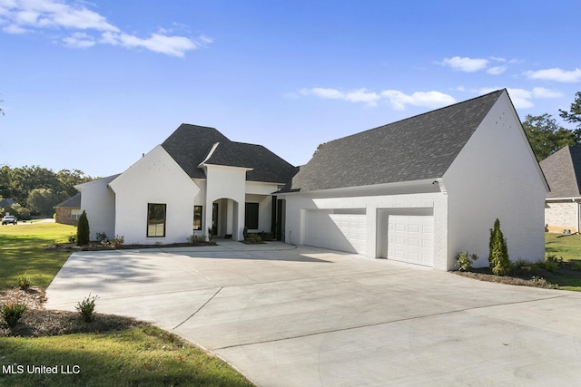 111 Grand Oak Blvd, Clinton, MS 39056 - french country style house featuring an attached garage, driveway, roof with shingles, and brick siding