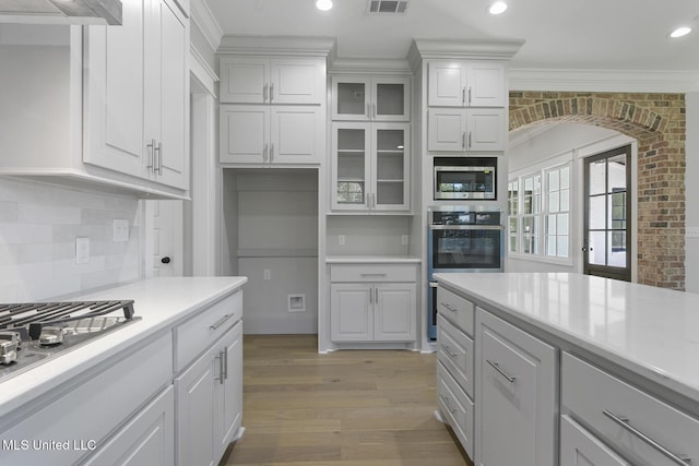 111 Grand Oak Blvd, Clinton, MS 39056 - kitchen with appliances with stainless steel finishes, crown molding, light wood-type flooring, light countertops, and arched walkways