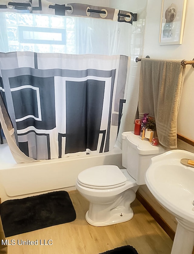 full bathroom featuring toilet, hardwood / wood-style floors, shower / bath combination with curtain, and sink