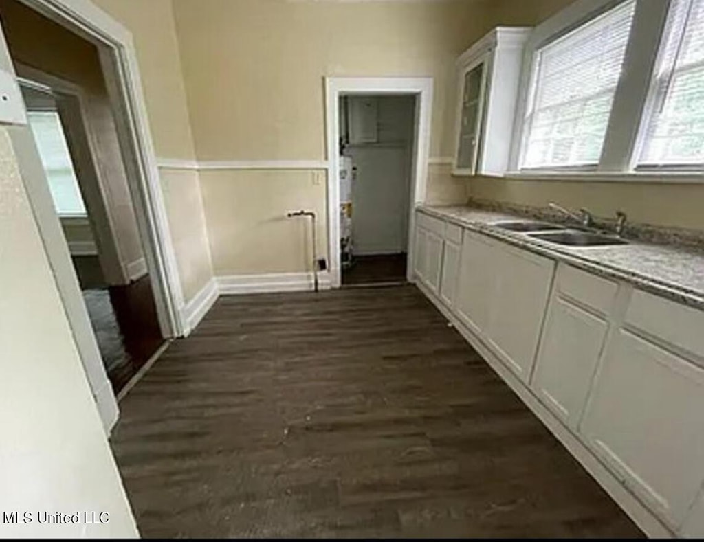 clothes washing area featuring a sink, dark wood-style flooring, and baseboards