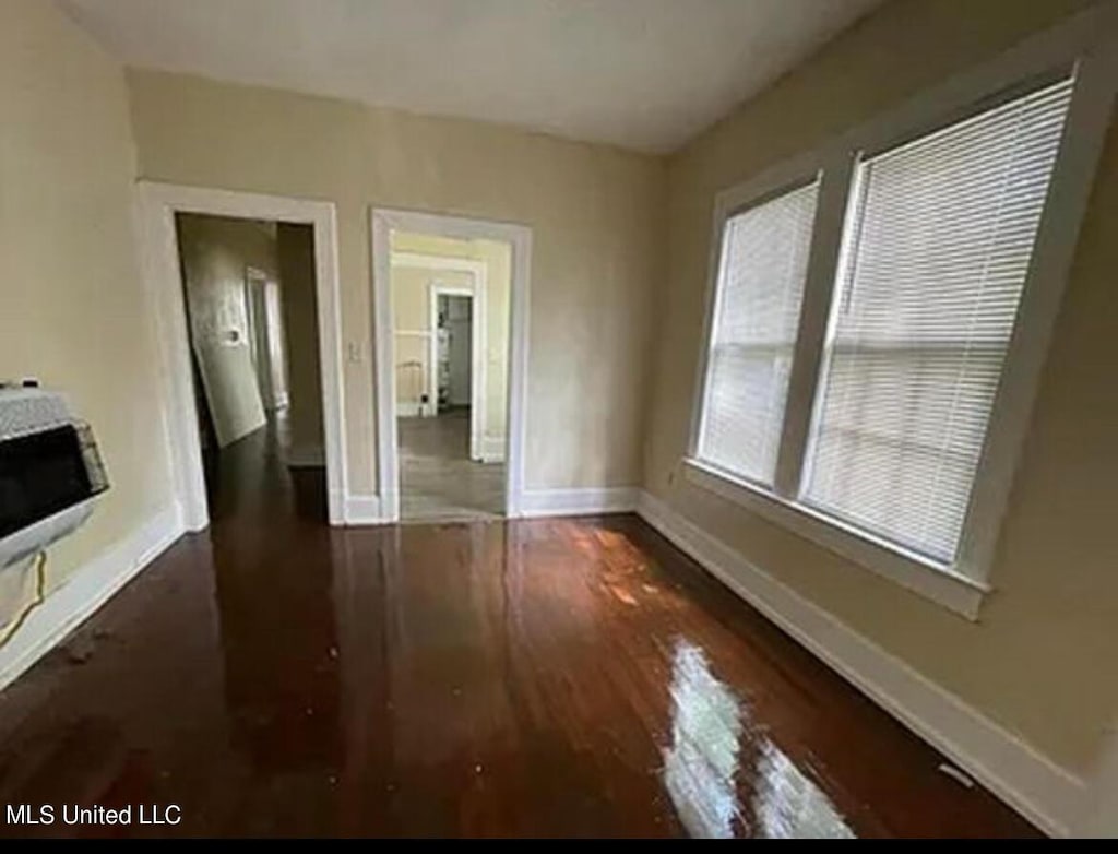 unfurnished living room featuring baseboards, heating unit, and dark wood-style flooring
