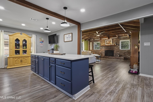 56 53rd St, Gulfport, MS 39507 - kitchen with blue cabinetry, brick wall, a fireplace, beam ceiling, and open floor plan