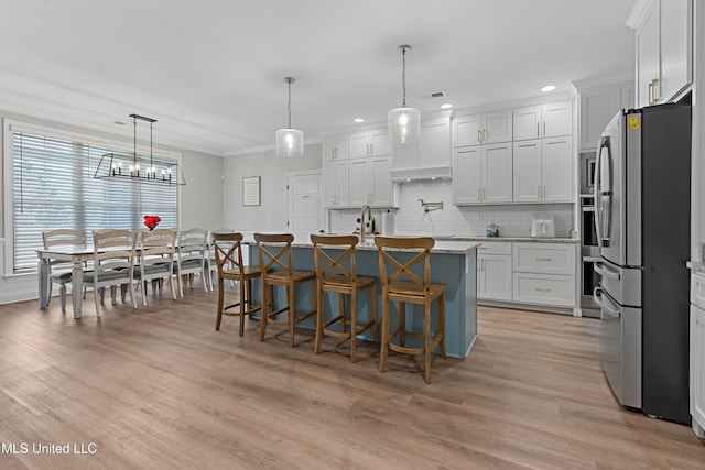 kitchen featuring visible vents, tasteful backsplash, light wood-type flooring, and freestanding refrigerator