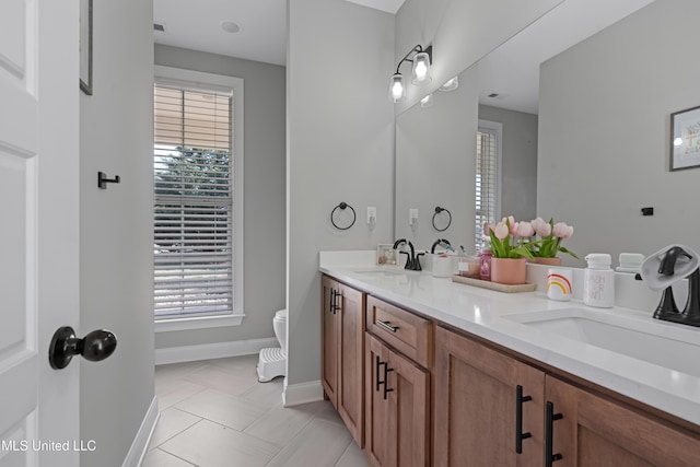 bathroom with tile patterned flooring, a sink, toilet, and double vanity