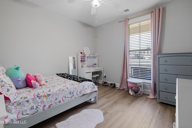 bedroom with baseboards, wood finished floors, visible vents, and a ceiling fan