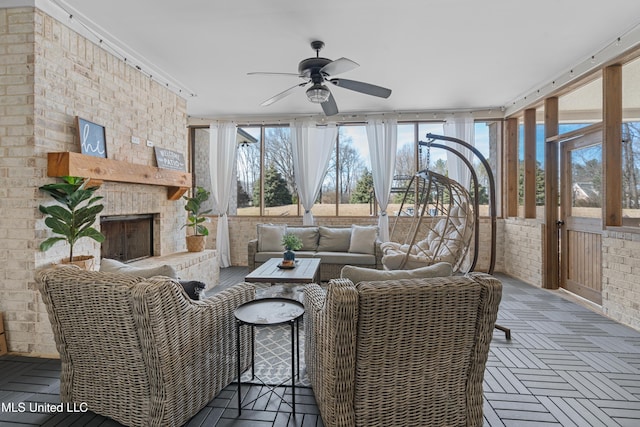 sunroom / solarium featuring a ceiling fan and a brick fireplace