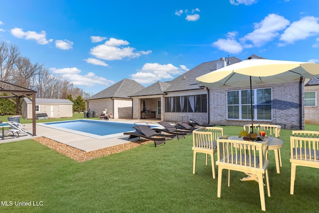 pool with a patio, a storage unit, a lawn, and an outdoor structure