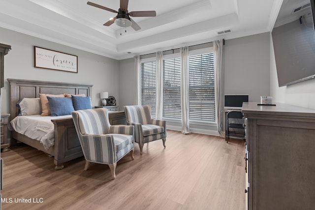 bedroom featuring light wood-style floors, visible vents, and a raised ceiling