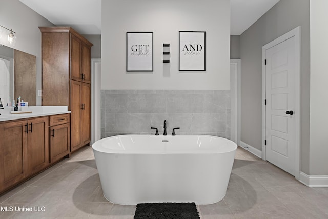 bathroom with a soaking tub, vanity, and tile walls