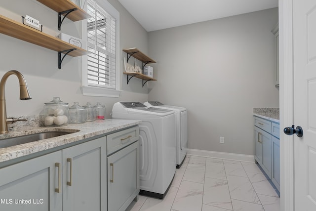 laundry area with cabinet space, baseboards, independent washer and dryer, marble finish floor, and a sink