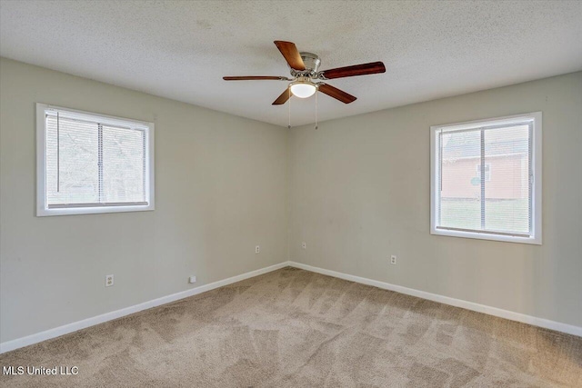 spare room with carpet flooring, a textured ceiling, and baseboards