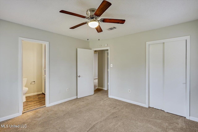 unfurnished bedroom featuring a textured ceiling, visible vents, carpet flooring, and ensuite bathroom